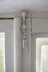 A dilapidated old window frame with a metal window latch. Renovation in an old house