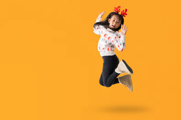 Cheerful young Asian girl wearing a Christmas sweater with reindeer horns, Happy smiling dance...