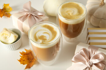Pumpkin coffee, leaves and gift boxes on white background