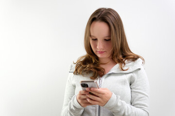 Portrait of tense concentrated female teenager with very long brown hair playing game on her cell phone being winner gesturing in joy over white background. Concept of emotions. High quality 4k