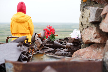  Grieving woman. Rusty remains of a gun from the Second World War on the stones. Monument to the war with carnations