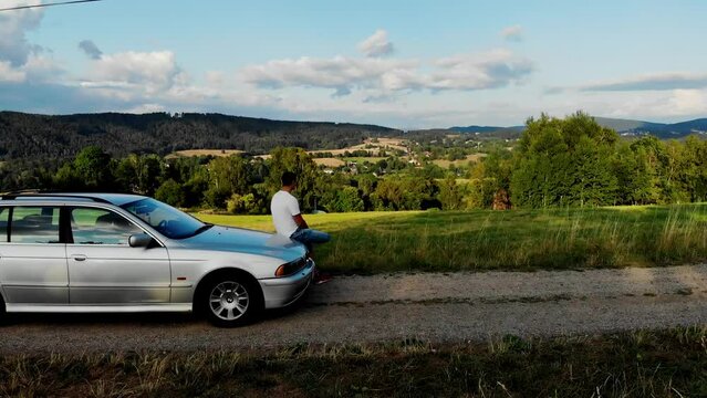 A young man sits in a car and admires the mountain landscape in the Czech Republic. View from a drone of Vratislavice, Liberec urban district in the Czech Republic. A drone view of a village