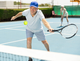 Portrait of emotional aged man enjoying friendly tennis match at outdoors court
