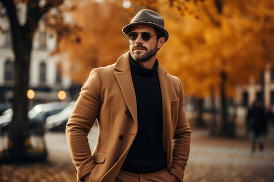 Men's autumn fashion.Handsome stylish adult Caucasian male model wearing sunglasses, brown coat and hat posing on city street on autumn day, lifestyle