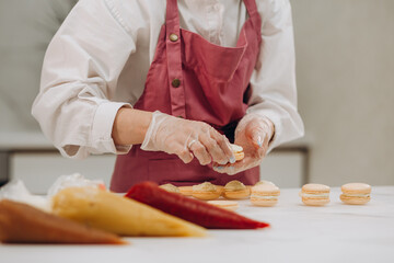 A confectioner makes macaroons in a pastry shop.