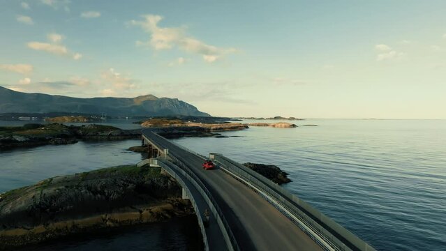 Aerial view of red SUV auto driving on epic Atlantic Ocean road in Norway