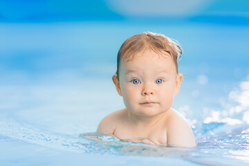 Fototapeta na wymiar Teaching happy baby girl in swimming pool, lesson for small swimmer