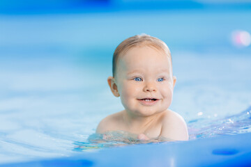 Fototapeta na wymiar Teaching happy baby girl in swimming pool, lesson for small swimmer