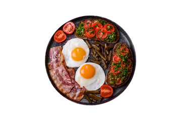 Tasty breakfast consists of eggs, bacon, beans, tomatoes, with spices and herbs