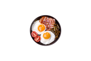 Tasty breakfast consists of eggs, bacon, beans, tomatoes, with spices and herbs