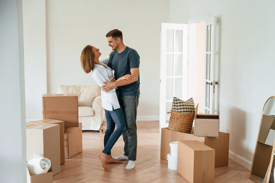 Dancing, celebrating. Young couple moving to new home
