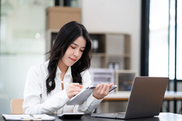Businesswoman working with tablet and using a calculator to calculate the numbers of static in...