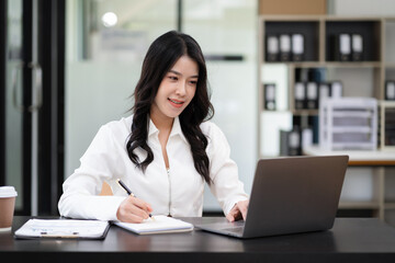 Business women writes information businessman working on laptop computer writing business plan in office.