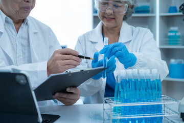 Fototapeta premium Medical Research Laboratory: Two scientists working, using digital tablets, analyzing samples, talking, developing biotechnology.