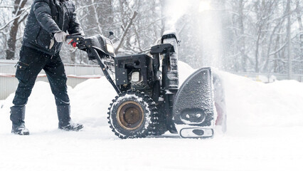 a janitor on a snowplow removes snow in the courtyard of a residential building - obrazy, fototapety, plakaty