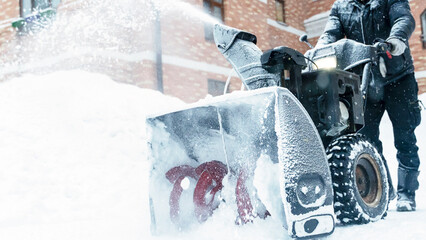 a janitor on a snowplow removes snow in the courtyard of a residential building - Powered by Adobe