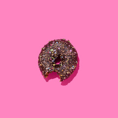 Top view of one chocolate donut on a pink background