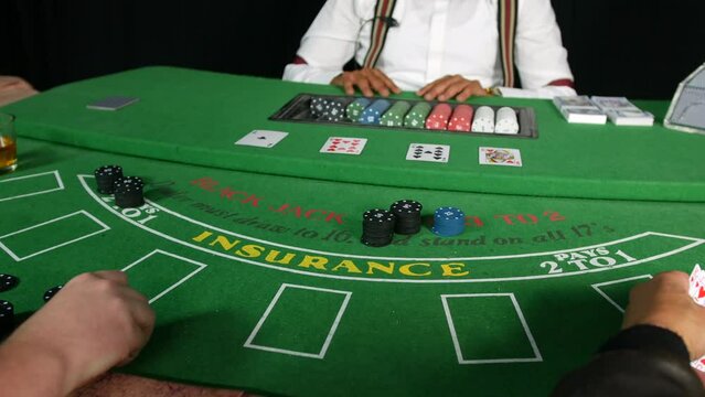 Poker players placing bets with poker chips on a black jack tabble in a casino