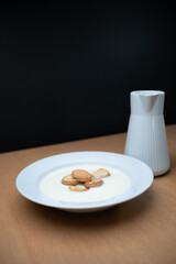 Bowl of milk product and cookies with jug on the side, made in white ceramic.