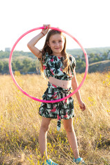 Little girl with a gymnastic hoop in nature in the summer