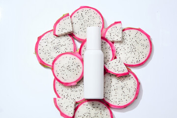 White bottle placed on a pile of many dragon fruit slices. Dragon fruit (Hylocereus) is rich in antioxidants which help fight free radicals. Branding mockup