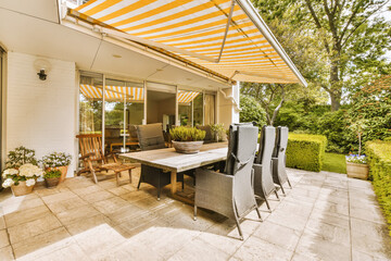 a patio with an umbrella over the dining table and chairs, in front of a white brick wall that has...