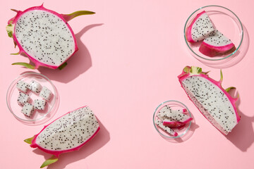 White dragon fruit cut in cubes and slices are arranged against pastel pink background. Blank space in the middle for beauty product presentation of Dragon fruit (Hylocereus) extract
