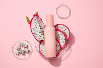 Few slices of white dragon fruit placed on a glass petri dish with an empty label bottle. Container...