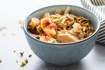 Multigrain breakfast cereals with fig, coconut chips, peanut butter and pistachio. Vegan breakfast concept.