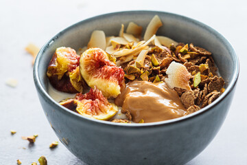 Multigrain breakfast cereals with fig, coconut chips, peanut butter and pistachio. Vegan breakfast concept.