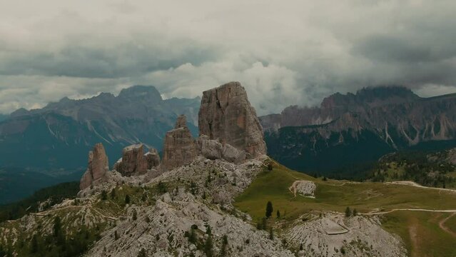 Parallax drone shot massive rock formations with distant tall mountains in the background, cloudy day, cinematic color grade