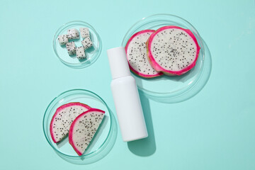 On the light background, unlabeled bottle in white color is decorated with white dragon fruit. Dragon fruits (Hylocereus) are essential for good eye health