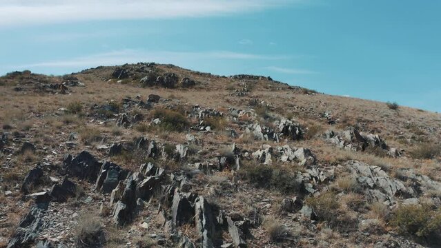 This stock video shows mountains overgrown with sparse vegetation and large rocks. This video will decorate your projects related to nature, travel, tourism.