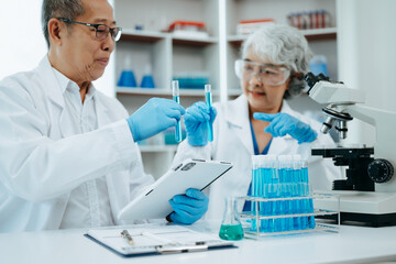 Two scientist or medical technician working, having a medical discuss meeting with Asian senior female scientist supervisor in the laboratory with online reading, test samples and innovation