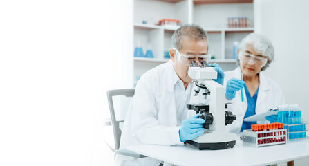 Asian senior Scientist team meeting and writing analysis results in the laboratory study and analyze scientific sample.
