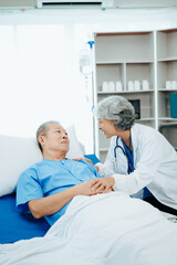 Obraz premium Asian doctor in white suit take notes while discussing and Asian elderly, man patient who lying on bed with receiving saline solution in hospital or clinic.