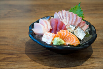 A tantalizing display of Japanese sashimi, elegantly served in a pristine bowl, resting on a rustic wooden table. Experience the vibrant colors and delicate freshness of this traditional delicacy.