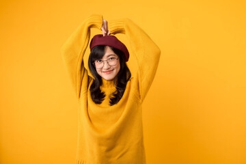 Smiling attractive Asian woman 30s wearing yellow sweater and red beret, has rouge cheeks, makes...