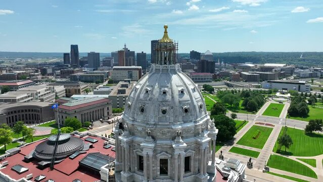 Minnesota capitol building with Saint Paul, MN skyline in background on bright summer day. Aerial orbit of government building dome.