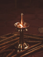 a traditional brass oil diya lamp with a burning flame during a religious pooja and festival for...