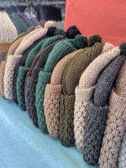 row of colorful knitted hats on shelf in store
