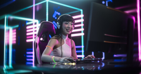 Fototapeta na wymiar Focused Japanese Young Woman Playing Video Games on a Computer in a Technologically Advanced Room with Futuristic Neon Background. Sci-Fi, Cyber Technology and Gaming Enthusiasts Concept