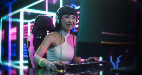 Obraz na płótnie Canvas Stylish Asian Streamer or Gamer in White Clothes Chats with Internet Fans on Computer in Futuristic Cyber Technology Room. Footage for Social Media, Streaming, and Gaming Content