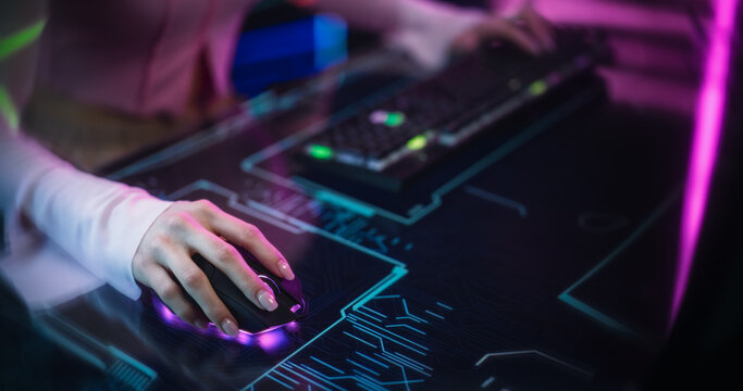Female Gamer Sitting Behind a Futuristic Interactive Desk in a Colorful Neon Studio Room. Young Woman Using a Keyboard and a Mouse on a Table with Technological Animation. Footage for Gaming Content