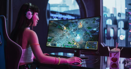 Focused Japanese Gamer Girl Playing Video Games on a Computer in a Technologically Advanced Room with Futuristic Neon Background. Sci-Fi, Cyber Technology and Gaming Enthusiast Concept © Gorodenkoff