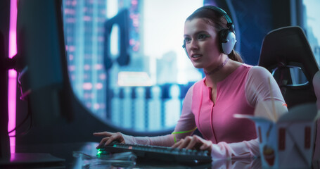 Stylish Young Woman Playing Video Games on a Desktop Computer in a Technologically Advanced Room with Futuristic Cyberpunk City in the Background. Sci-Fi Technology and Gaming Tournament Concept © Gorodenkoff