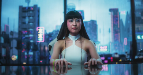 Stylish Japanese Young Woman Interacting with Augmented Reality Platform in a Technologically Advanced Room. She is Using Glass Interactive Desk with Futuristic Cyberpunk City in the Background.