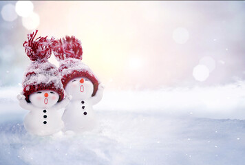Two little snowmen in caps on snow in the winter. Background with a funny snowman. Christmas card. - 646768172
