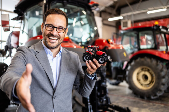 Tractor salesman standing in workshop and guarantee spare parts and service of agricultural machines.