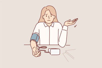 Woman measures blood pressure with electronic tonometer, sits at office desk and feels worse